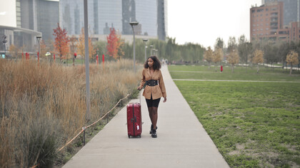 Young woman walking down a city street with a suitcase