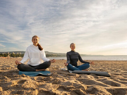 A mother and daughter gracefully engaging in yoga by the beach, epitomizing the harmony of family connection and health amidst nature's beauty