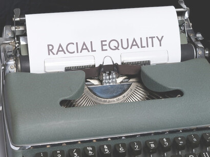 A typewriter rests beside a sheet of paper bearing the words "racial equality"