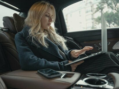 A woman working on a laptop while traveling, representing the expectation to remain productive wherever we are