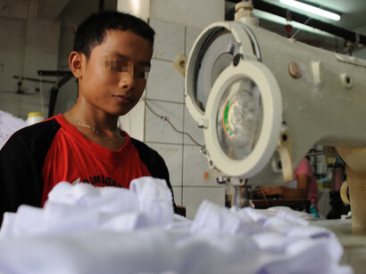 Child workers at a small garment factory in Jakarta, Indonesia, perform tasks such as sewing and packaging