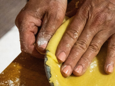 Hands shape pie crust dough on a wooden board, reflecting the care and craftsmanship of traditional home baking