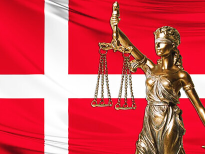 A statue of justice stands proudly against the backdrop of the Danish flag, symbolizing the nation's commitment to fairness and equality