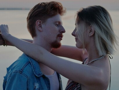 Homem e mulher se olham frente ao oceano