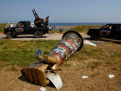 Graffiti-covered monument of a fist depicted crushing a U.S. fighter jet that once stood in Tripoli, Libya. The famous sculpture was toppled during the 2011 civil war and is now reportedly in a Libyan museum © Francois Mori/AP