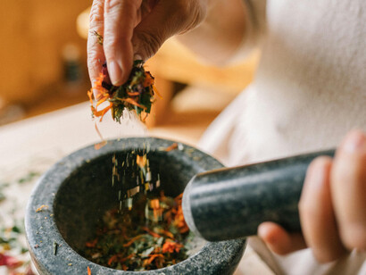 In a nod to ancient Indian medicine, a person pounds dried flowers with a mortar and pestle—capturing the essence of Ayurvedic detox and healing