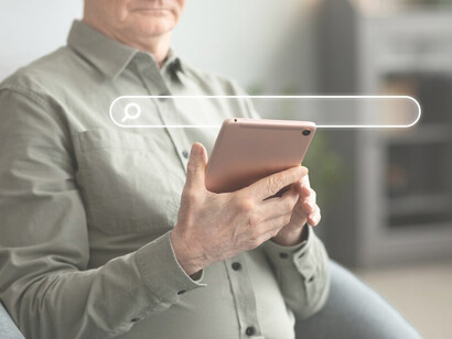 Individual interacting with a phone displaying a search bar, highlighting AI search results and Google's advanced search engine integration