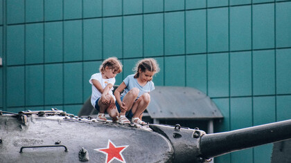 Crianças sentadas em cima de um canhão de guerra na Rússia