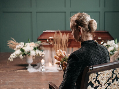 A woman mourns the loss of a loved one at a funeral, surrounded by flowers and remembrance