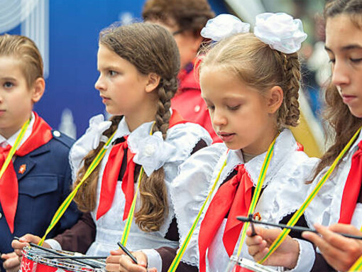 Children wearing Soviet school uniforms perform on drums as members of the Young Pioneers