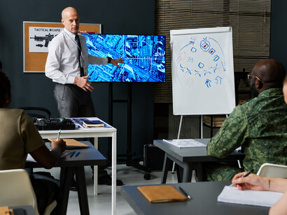 Instructor explaining military tactics on a whiteboard filled with strategic diagrams and movement arrows