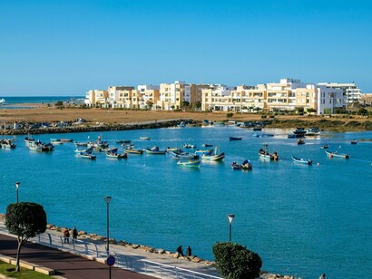 Boats scattered across the Bouregreg waterfront in front of Rabat’s contemporary architecture, reflecting the continuity of Moroccan identity through changing times