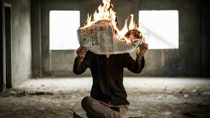 Homem segurando jornal em chamas. O que pode parecer, pode não ser… 
