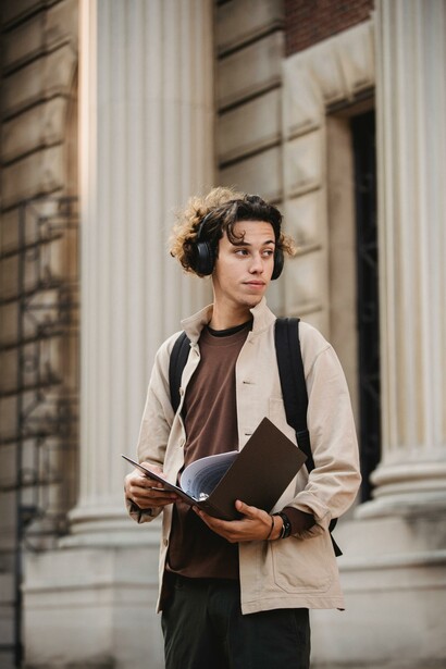 A person wearing headphones holding a folder of notes 