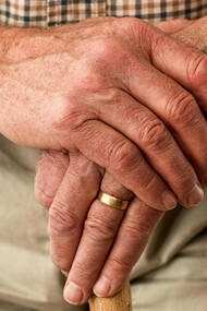 Dettaglio di mani di un anziano che si appoggiano ad un bastone