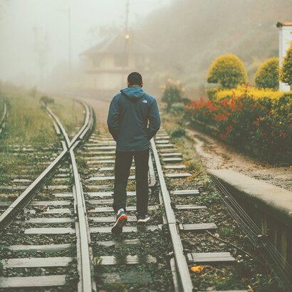 Man walking on foggy train tracks in Sri Lanka, a scene reflecting heartbreak and isolation