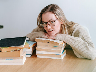 A young woman absorbed in a book, sitting near a stack of literature