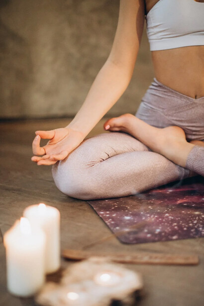 Ragazza che medita in casa con delle candele accese