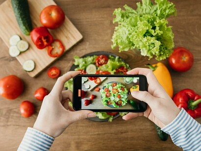 Someone using a smartphone to scan fresh vegetables, utilizing AI-powered meal planning to create a personalized diet based on their DNA and gut microbiome