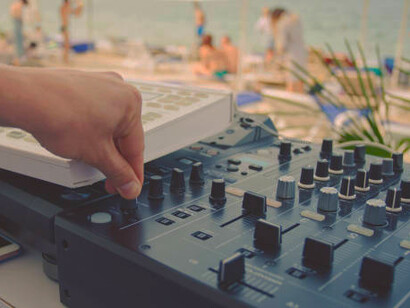 Summer beach party at sunset with a DJ playing music outdoors
