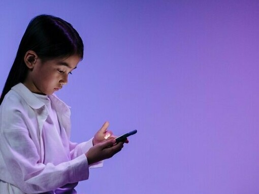 A child absorbed in her smartphone, reflecting the erosion of attention and independent thought in the digital age