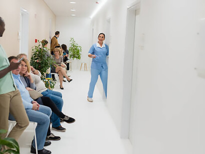 A bustling hospital corridor with patients gathered in seats and standing as they wait for care