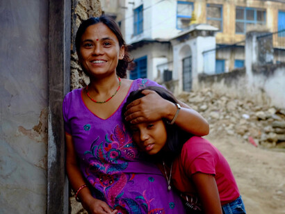 A mother and daughter share a smile in an urban setting in India
