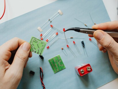 Hands working with circuitry and electronic components, reflecting the human ingenuity driving the development of advanced technology