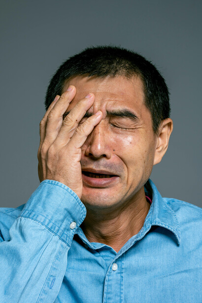 A worried man in a blue denim button-up shirt, gripped by anxiety and fear