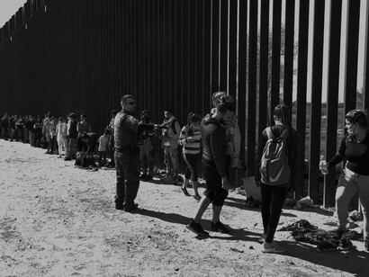 A US Customs and Border Protection officer directs migrants seeking asylum into vans before transferring them to temporary shelters in Yuma, Arizona, USA