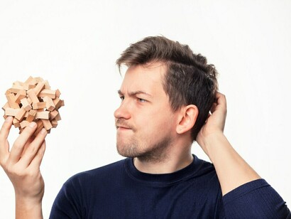 A man staring at a wooden puzzle represents the complexity of decision-making, where cognitive biases and emotional responses often come into play