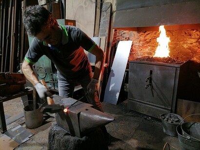 Un fabbro che modella un pezzo arroventato battendo con il martello sull'incudine, Girona, Spagna
