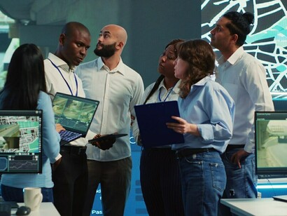 A diverse group of employees collaborates on geospatial technology projects, leveraging generative AI, machine learning, data visualization, and satellite imagery to drive digital transformation