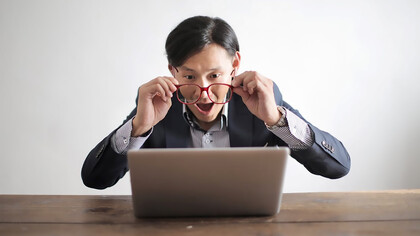 An entrepreneur looking at his laptop with surprise and happiness