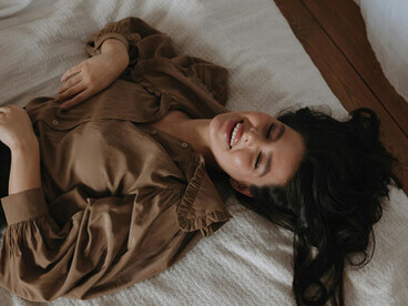 A gentle portrait of self-discovery—a person smiling in bed, representing personal truth, self-acceptance, and emotional honesty