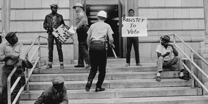 Sheriff Jim Clark arrests two demonstrators who displayed placards on the steps of the federal building in Selma, 1963. Gelatin silver print, 11 x 14 inches. © Danny Lyon, New York & Magnum Photos, New York / Courtesy Edwynn Houk Gallery, New York.