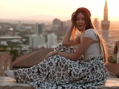 A woman sitting peacefully above the bustling city, symbolising the longing for a life defined by purpose rather than performance