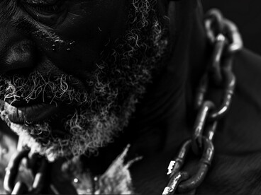 A clenched fist gripping a chain captures resistance within oppression, pointing to how those exploited by slavery were forced to fight against a system designed to divide and control both race and class
