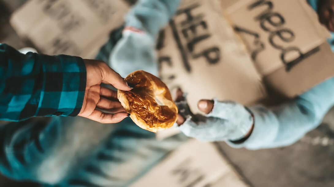 A person begging under a bridge receiving bread from another individual, highlighting acts of generosity, reciprocity, and kindness in giving and receiving