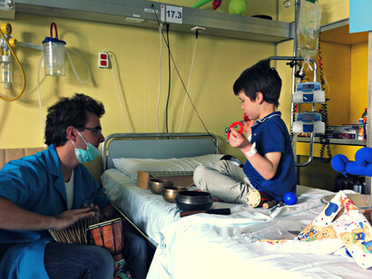 Un musicoterapeuta del progetto Tamino intrattiene un piccolo paziente