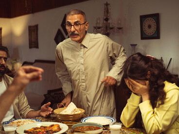 A family sits in silence during a tense disagreement around the dinner table indoors