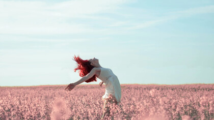 Ragazza si lascia cullare dal vento in un prato di fiori: ricordate sempre di essere la vostra causa e non l’effetto di quel che capita intorno a voi