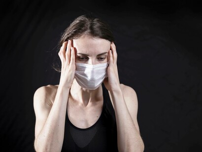 A young person is placing hands on her temples attempting to lessen the feeling of stress that is invading their life