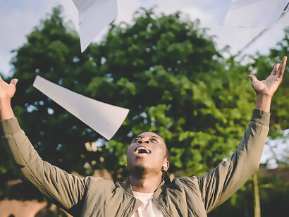 With unbridled joy, a man gleefully scatters papers into the air, symbolizing triumph, motivation, ambition, and the realization of his goals