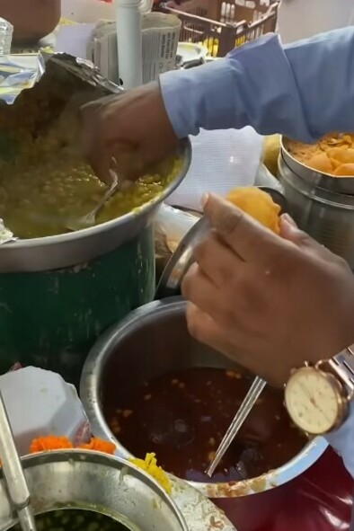 Man preparing gol gappa at a bustling street food stall in Mumbai, India