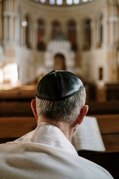A man in a kippah sits in prayer while reading the Bible