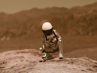 Astronauta examina o solo de uma paisagem desértica que remete a ambientes extraterrestres. A busca por vida além da Terra continua sendo uma das maiores questões da ciência moderna. A possibilidade de outras civilizações no universo permanece objeto de estudo e especulação