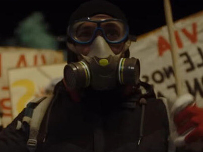 With an ominous presence, the protestor stares ahead, a symbol of resistance, as tensions mount between those challenging the system and those who enforce it