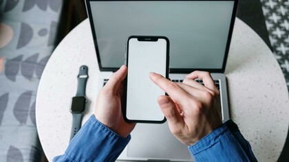 Jovem utiliza celular, relógio digital e laptop