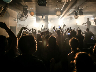 People dancing and celebrating on a crowded dance floor with club music and lighting